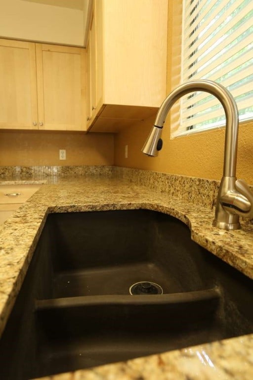 room details featuring light stone counters, light brown cabinetry, and sink