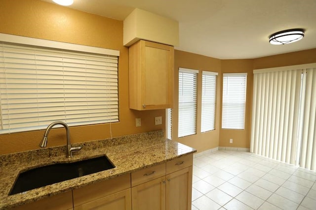 kitchen with sink, light brown cabinetry, light stone counters, and light tile patterned floors