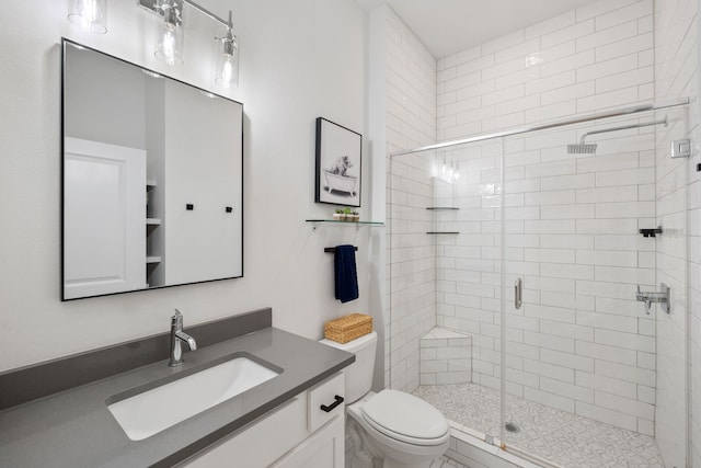 bathroom with a shower with shower door, toilet, and vanity