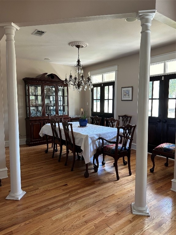 dining area featuring hardwood / wood-style floors, a notable chandelier, and french doors