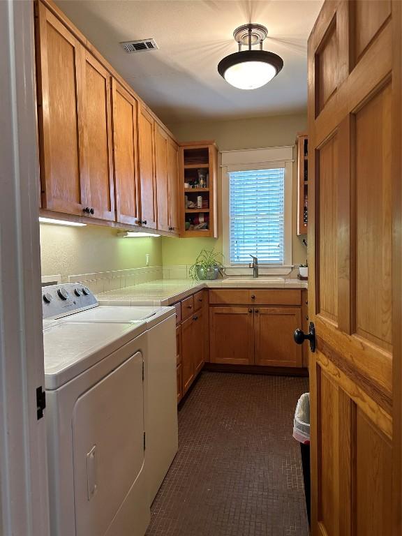 washroom with sink, independent washer and dryer, and cabinets