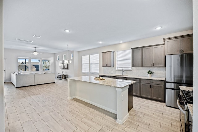 kitchen featuring sink, light stone countertops, appliances with stainless steel finishes, and a wealth of natural light