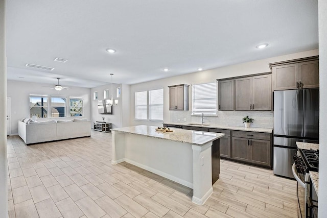 309 Greenway Dr, Georgetown, TX 78628 - kitchen with a center island, a sink, a healthy amount of sunlight, dark brown cabinetry, and appliances with stainless steel finishes