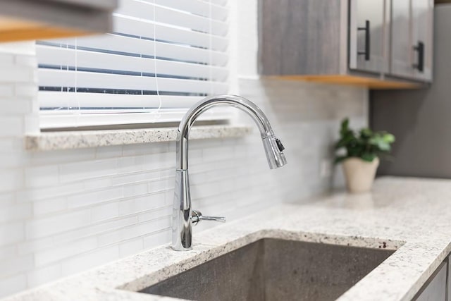 309 Greenway Dr, Georgetown, TX 78628 - details with decorative backsplash, a sink, light stone counters, and gray cabinets