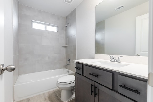 full bathroom with toilet, tiled shower / bath, hardwood / wood-style flooring, and vanity