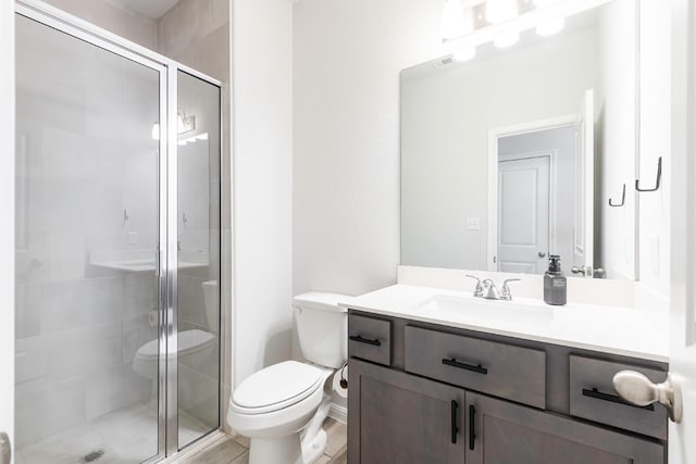 bathroom featuring vanity, hardwood / wood-style floors, a shower with shower door, and toilet