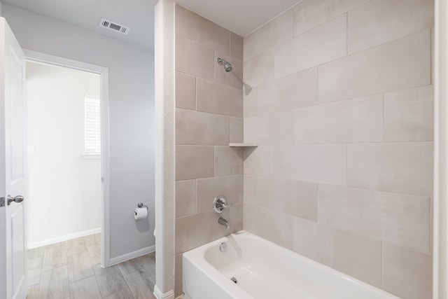 bathroom with tiled shower / bath and wood-type flooring