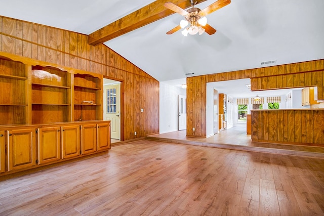 unfurnished living room with ceiling fan, vaulted ceiling with beams, light hardwood / wood-style floors, and wood walls