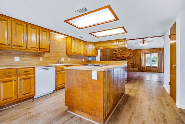 kitchen with wood walls, a kitchen island, white dishwasher, ceiling fan, and light hardwood / wood-style flooring