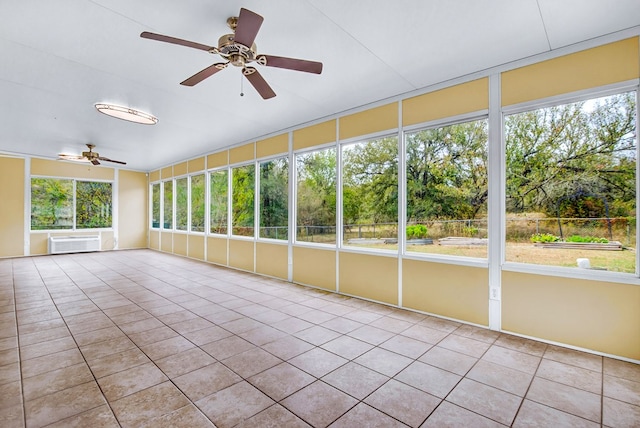 unfurnished sunroom featuring a wall mounted air conditioner, a healthy amount of sunlight, and ceiling fan