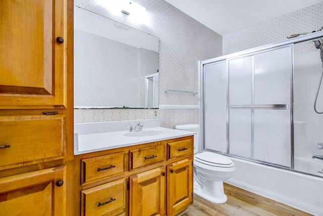 298 Jenkins Rd, Cedar Creek, TX 78612 - full bathroom featuring wallpapered walls, toilet, vanity, wood finished floors, and enclosed tub / shower combo