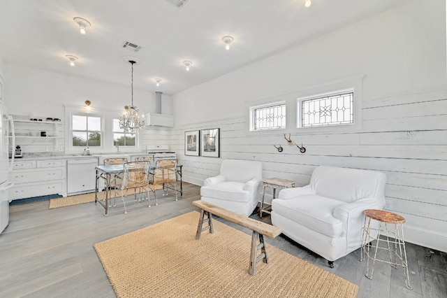 sitting room with wood-type flooring, an inviting chandelier, and wooden walls