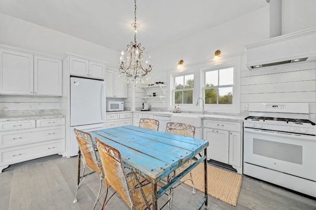 kitchen with white appliances, light hardwood / wood-style floors, white cabinetry, and decorative light fixtures