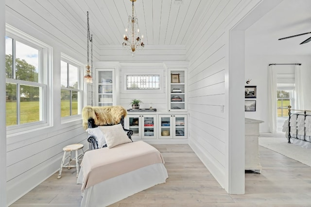 living area featuring a notable chandelier, light wood-type flooring, and wood walls