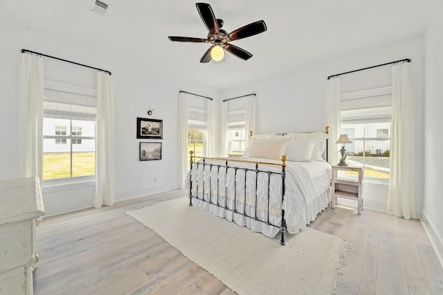 bedroom with ceiling fan, multiple windows, and light wood-type flooring