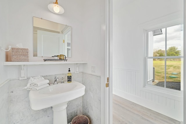 bathroom with a healthy amount of sunlight, hardwood / wood-style flooring, and tile walls