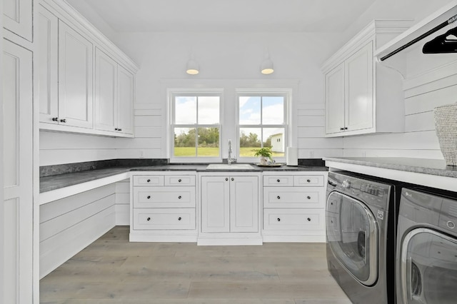 clothes washing area featuring cabinets, light hardwood / wood-style flooring, washer and dryer, and sink