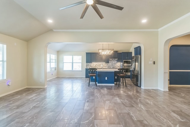 kitchen featuring a center island with sink, hanging light fixtures, a kitchen breakfast bar, appliances with stainless steel finishes, and crown molding