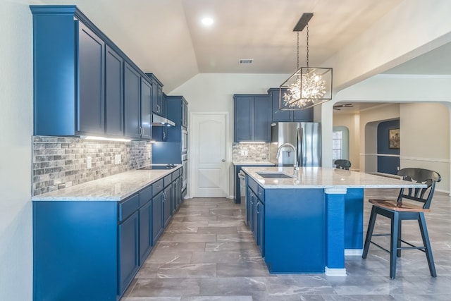 kitchen with sink, an island with sink, blue cabinets, decorative light fixtures, and decorative backsplash