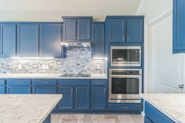 kitchen with blue cabinets, appliances with stainless steel finishes, and extractor fan