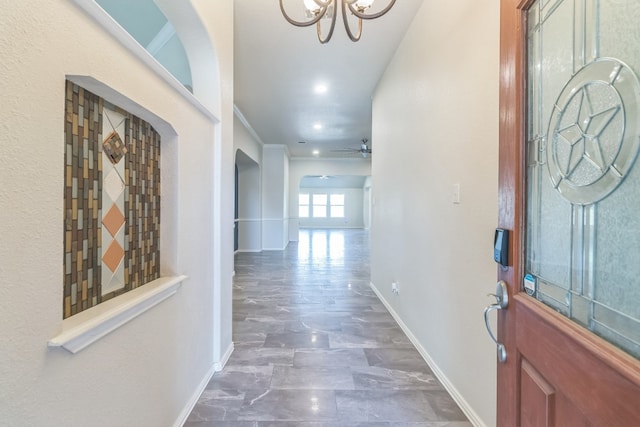 entryway with ornamental molding and ceiling fan with notable chandelier