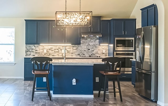 kitchen with light stone counters, stainless steel appliances, a breakfast bar, and a kitchen island with sink