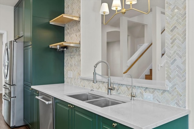 kitchen featuring decorative backsplash, sink, light stone countertops, green cabinetry, and stainless steel refrigerator