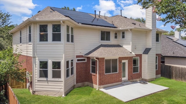 rear view of property featuring a patio area, solar panels, and a yard