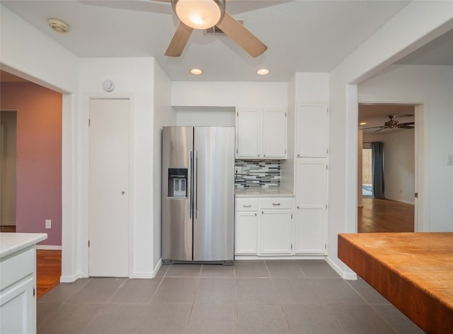 kitchen featuring stainless steel refrigerator with ice dispenser, white cabinets, light tile patterned floors, and backsplash