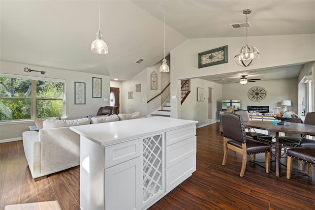 kitchen with lofted ceiling, white cabinets, decorative light fixtures, and dark wood-type flooring