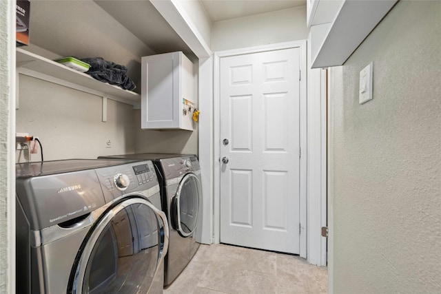 clothes washing area with cabinets, independent washer and dryer, and light tile patterned floors