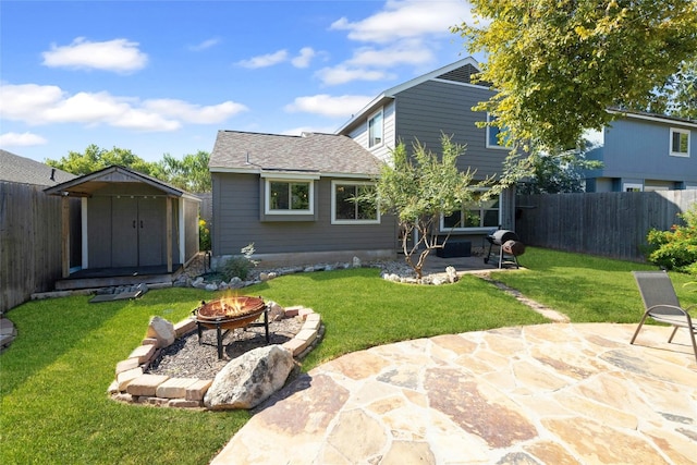 rear view of house featuring a lawn, a storage shed, a patio, and an outdoor fire pit