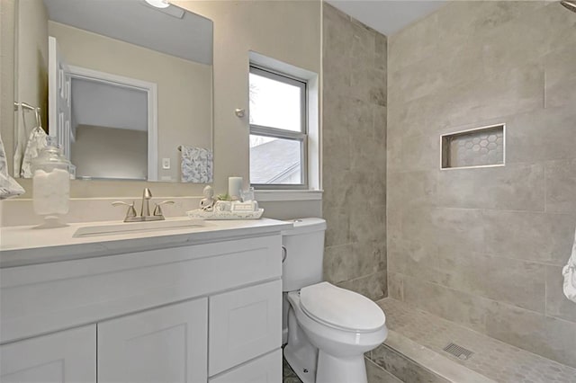 bathroom featuring vanity, toilet, and a tile shower