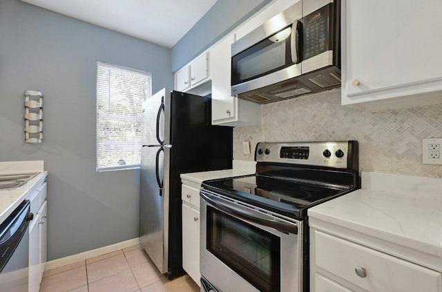 kitchen featuring backsplash, light tile patterned flooring, white cabinetry, appliances with stainless steel finishes, and light stone counters