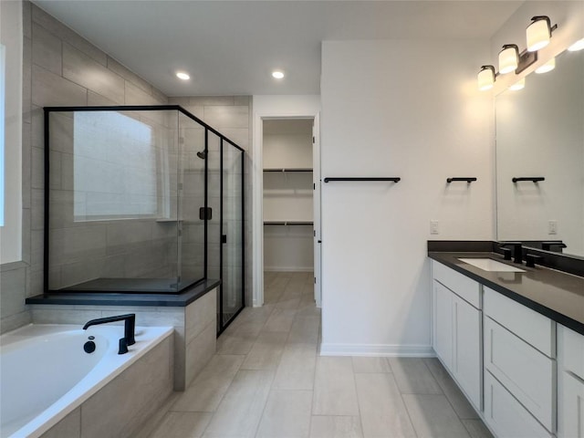 full bath featuring a walk in closet, baseboards, a stall shower, a bath, and vanity