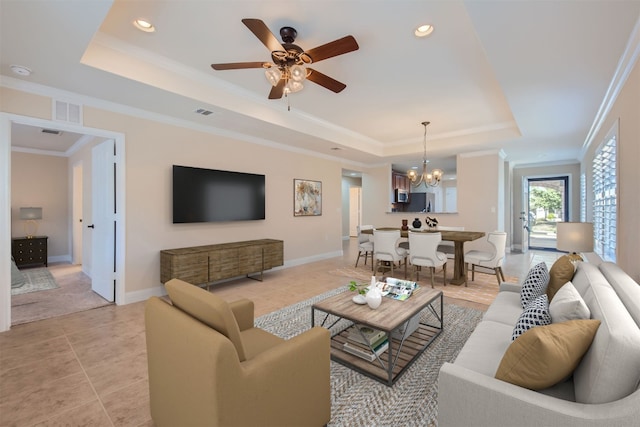 tiled living room featuring a tray ceiling, ceiling fan with notable chandelier, and ornamental molding