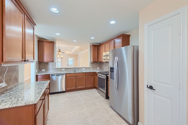 kitchen with light stone countertops, tasteful backsplash, stainless steel appliances, ceiling fan, and sink