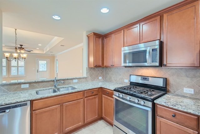 kitchen with sink, light stone counters, backsplash, a chandelier, and appliances with stainless steel finishes