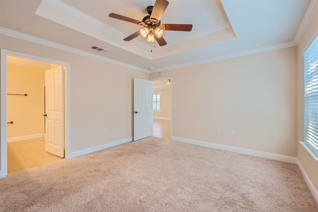 unfurnished bedroom featuring a tray ceiling, ceiling fan, light carpet, and ornamental molding