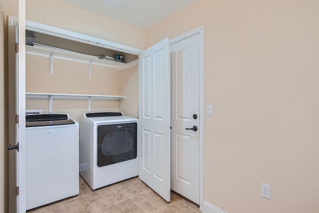 clothes washing area with washer and dryer and light tile patterned floors