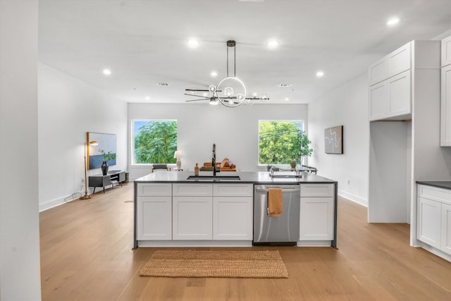 kitchen with sink, pendant lighting, stainless steel dishwasher, white cabinets, and light hardwood / wood-style flooring