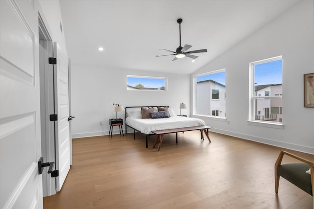 bedroom featuring ceiling fan, vaulted ceiling, multiple windows, and light wood-type flooring