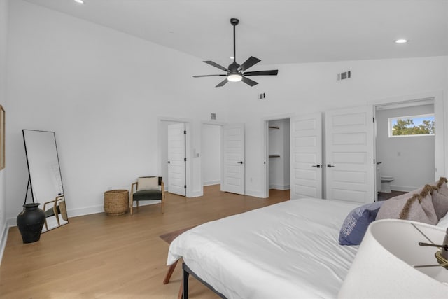 bedroom with hardwood / wood-style floors, ensuite bathroom, high vaulted ceiling, and ceiling fan