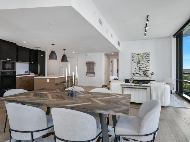 70 Rainey St Unit 1408, Austin, TX 78701 - dining area with light wood-type flooring, track lighting, floor to ceiling windows, and recessed lighting