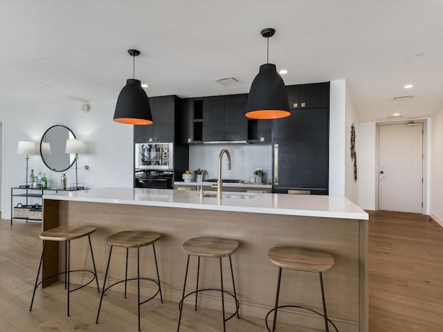 kitchen featuring light hardwood / wood-style flooring, black oven, and decorative light fixtures