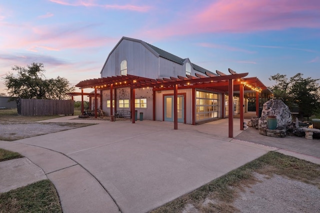 patio terrace at dusk featuring fence and a pergola