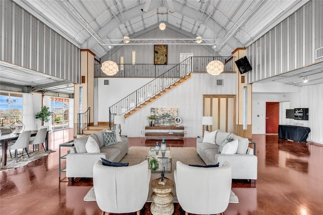 living room with high vaulted ceiling, stairway, finished concrete flooring, and metal wall