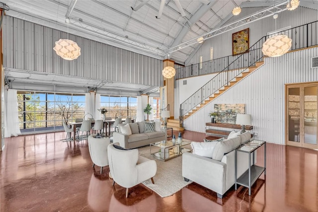 living room featuring high vaulted ceiling, stairway, metal wall, and finished concrete floors