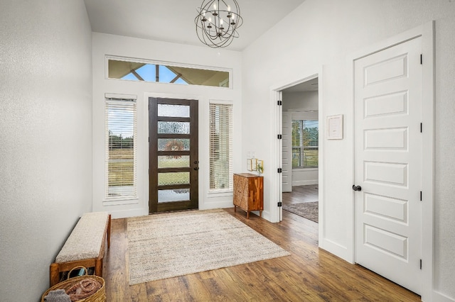 foyer entrance with a chandelier, vaulted ceiling, and wood-type flooring