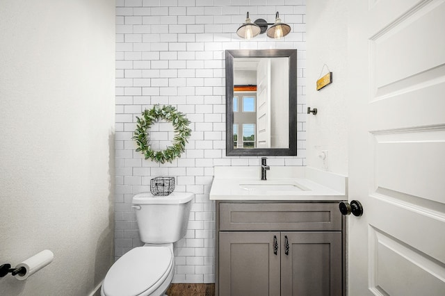 bathroom with tile walls, vanity, and toilet